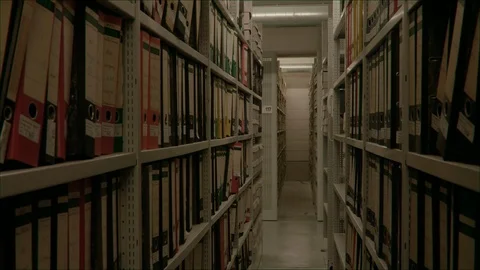 Slow camera movement between two archive shelves filled with folders. Stock-Footage 95429661
