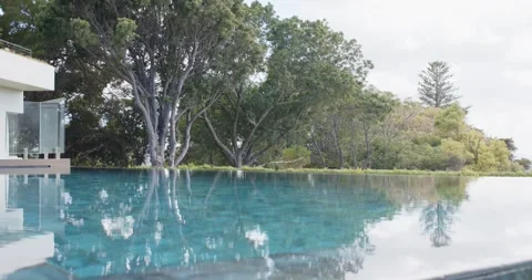 Slow camera movement is bringing infinity pool closer at home, revealing tree Stock Footage 341938125