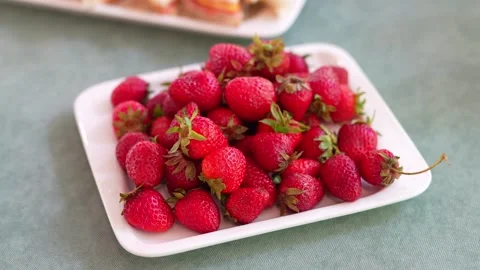 Slow camera pan over fresh red strawberries on white platter Stock Footage 335579935