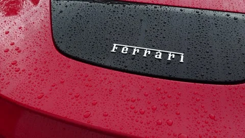 Slow camera pan over the silver Ferrari logo emblem on a red car trunk lid Stock Footage 340755691