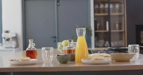 Slow camera pull is drawing juice carafe and pancakes closer on island, Stock Footage 339415466