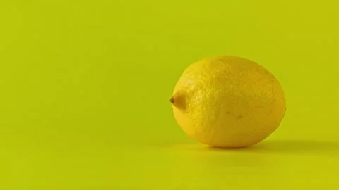 Slow camera push-in on a fresh, whole lemon on a vibrant yellow background. Stock Footage 338182326