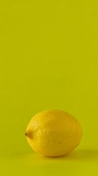 Slow camera push-in on a fresh, whole lemon on a vibrant yellow background. Stock Photos