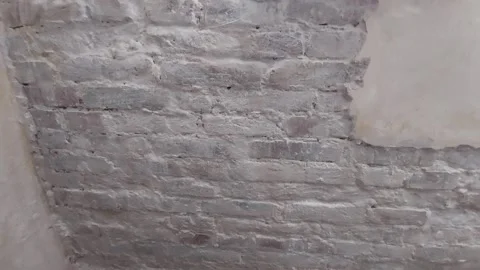 Slow camera tilt of an old white painted brick wall with cracked and peeling pla Stock Footage 336482709