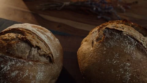 Slow cinematic pan over artisan sourdough bread loaves on decorated table Stock Footage 343549779
