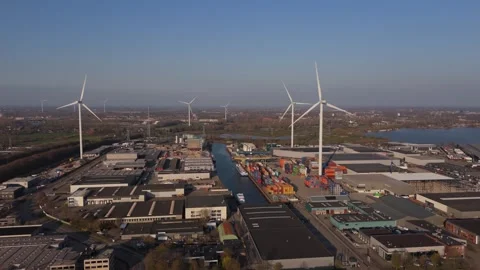 Slow close aerial orbit of wind turbines and industrial port Stock Footage 335658645