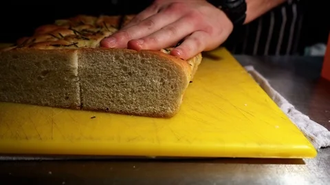 Slow close up of chef cutting down the middle of garlic bread Stock Footage 106810620