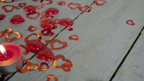 Slow close-up slide of lighted up candles on the wood table with red hearts Video stock 85285928