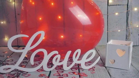 Slow close-up slide shot of Love sign with red hearts, lights and red baloon on Video stock 85246151