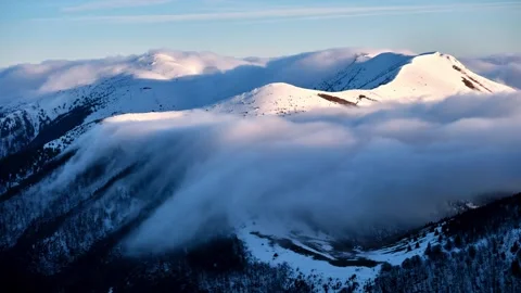 Slow cloud inversion timelapse flowing over snowy winter mountain ridge in soft Stock-Footage 321751605