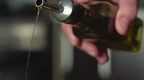 SLOW: A cook pours olive oil from oil bottle Видео 63393052