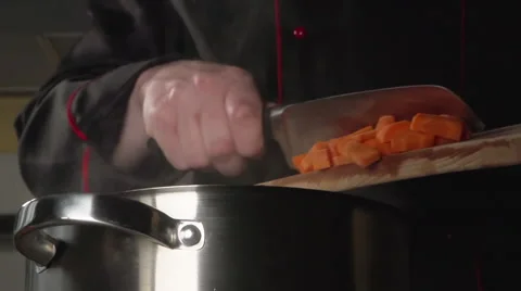 SLOW: Cook throws a sliced carrot into a steel pan Stock Footage 63626236