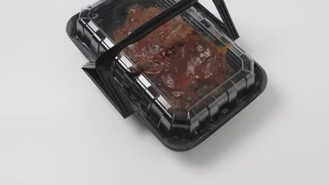 Slow-cooked barbecue ribs covered in thick sauce in a black plastic takeawa.. Stock Footage 333978814