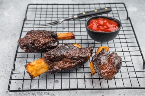Slow cooked beef short ribs with bone and BBQ sauce on grill rack. Tender b.. Stock Photos