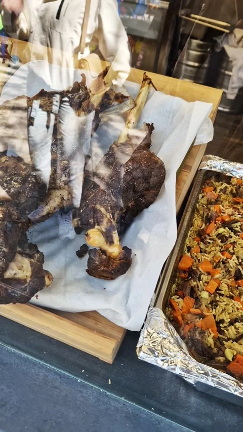 Slow Cooked Bone-In Lamb Shanks Behind Deli Glass Display at Street Food Stall Stock Footage 339077285