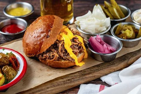 Slow cooked pulled rib beef burger with melted cheese and sides Stock Photos