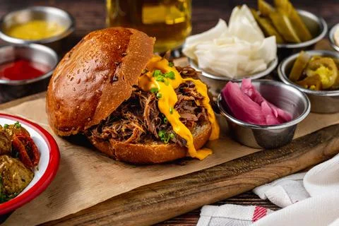 Slow cooked pulled rib beef burger with melted cheese and sides Stock Photos