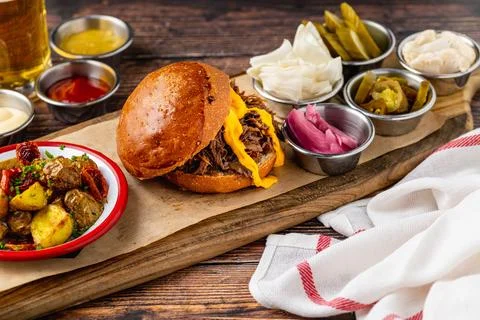 Slow cooked pulled rib beef burger with melted cheese and sides Stock Photos