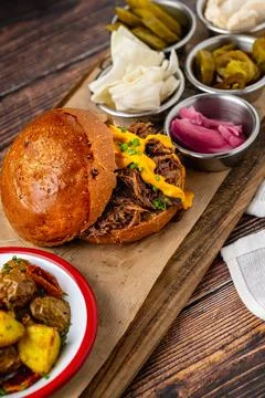 Slow cooked pulled rib beef burger with melted cheese and sides Stock Photos