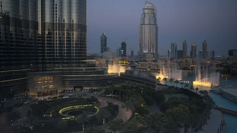 Slow descent down Burj Khalifa, track forward towards dubai fountain at 60m, Stock Footage 98959397