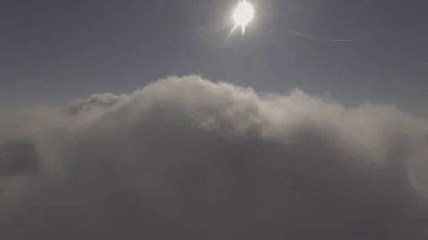 Slow descent into forming clouds with the sun in front, 4K Stock Footage 72907990