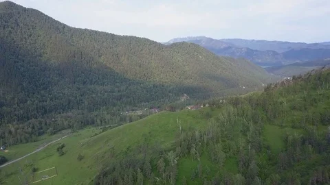 Slow direct aerial flight over mountain village, forest, country road 動画素材 84582413