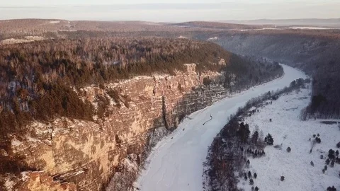 Slow direct aerial flight over a frozen mountain river, rocks and forest. 動画素材 84740968
