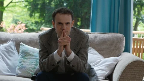 Slow Dollly of Man Thinking Intently on the Sofa Stock Footage 89922726