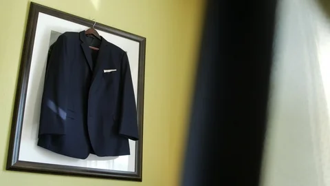 Slow dolly away from suit jacket hanging on picture frame Vídeos de archivo 111400646