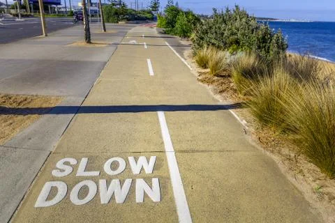 Slow Down sign written on shared footpath for cyclists and pedestrians Stock Photos