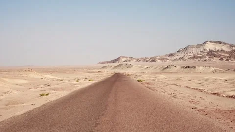 Slow driving motion by the sandy road through the wild desert. Clear blue sky Stock Footage 253893493