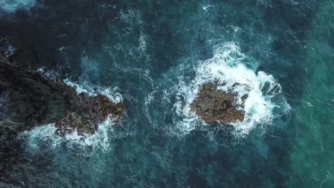 Slow drone drift across a lone sea stack circled by foam, background plate for Stock Footage 344530265