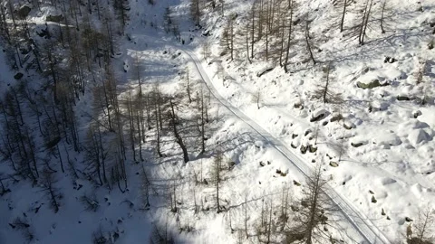 Slow drone flight in mountain over an isolated small road covered with snow 4k Stock Footage 148031239