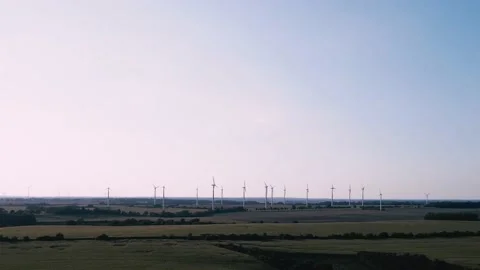 Slow drone flight over fields during pink sunset with wind turbines on horizon Stock Footage 161074838