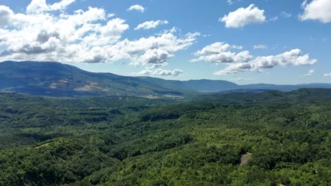 Slow drone flight over lush green mountain valley in sunlight Stock Footage 323503860