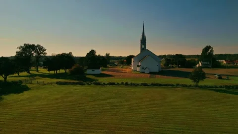 Slow Drone Flight Over Vibrant Green Grass Towards A White Church With Tower Stock Footage 255350179