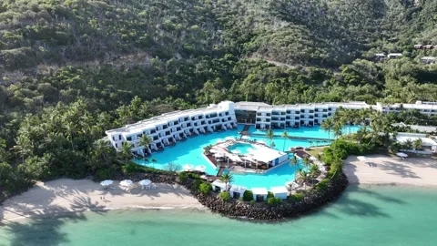 Slow drone orbit in daytime around Hayman Island’s lagoon pool and beachfront Stock Footage 331025790