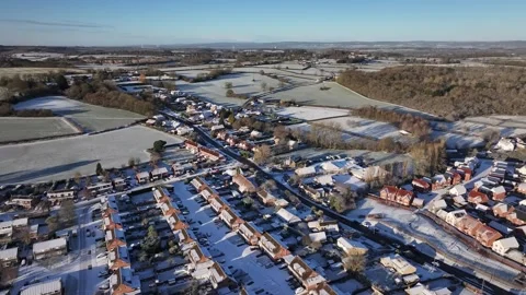 Slow Drone Pan over Small Snow covered UK village main road in 4K Видео 329968216