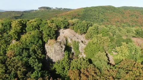 Slow Drone Pan of Rocky Cliff Emerging from Dense Green Forest 動画素材 337305395