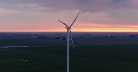 Slow drone parallax around utility scale wind turbine at sunset above farmland Stock Footage 340283312
