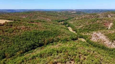 Slow drone pullback over wooded limestone hills and dry scrub in the Lot Stock Footage 346076074