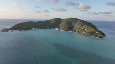 Slow drone pullback with a subtle rise at golden hour, widening over Hayman Stock Footage 331025327