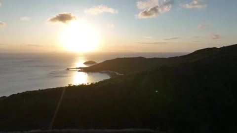 Slow drone push-in along a lush island ridgeline at sunset, revealing golden Видео 331062766