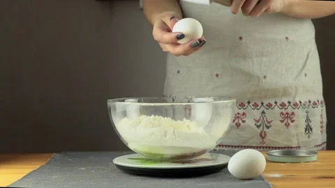 SLOW: Egg falls on a pile of flour on a black background Stockbeeldmateriaal 74805119