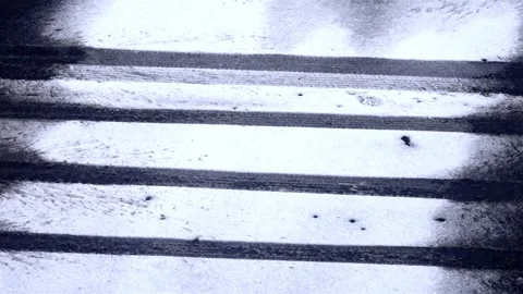 Slow falling snowflakes on a street, pattern of the car wheels in the snow 動画素材 301632045