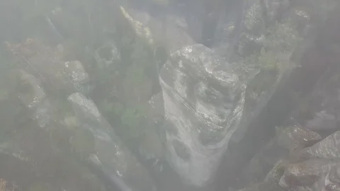 Slow flight above the rocks turning camera down in the fog Stock Footage 115602989