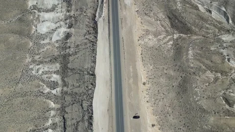 Slow flight at high altitude over a highway in a mountainous desert Stock Footage 237693566