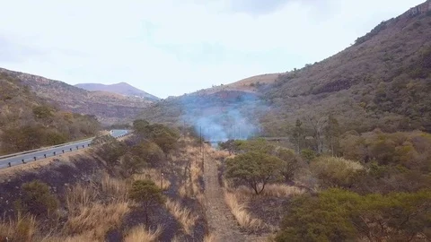 Slow flight over burnt patch near valley road in South Africa Stock Footage 78584221
