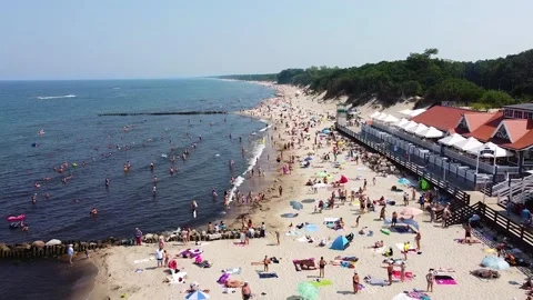 Slow flight over a sandy beach with crowds of people sunbathing on the sea coast Stock Footage 178370229