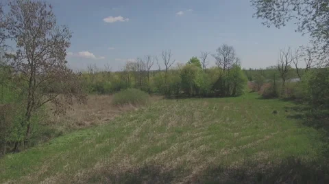 A slow flight over a small field to reveal a river for CC Video stock 63929853